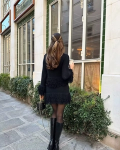 Rear view of an elegant black knit set featuring long fringe details on top and midi skirt