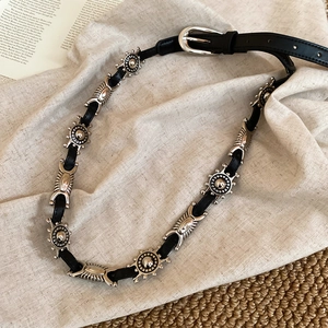 Detail of black leather belt featuring silver sun-patterned concho studs and buckle