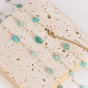 Gold chain necklace with irregular light green stone beads and pearls on stone base