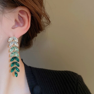 Close-up of leaf tassel earrings with green gradient crystals on a female model
