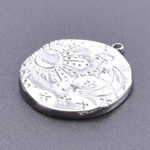 Detail of silver stainless steel sun moon and stars pendant on grey textured background