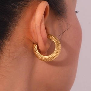 Detailed view of large gold C-shape earrings with scale texture on a female model