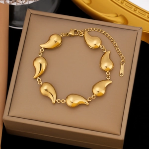 Macro view of golden stainless steel bracelet with teardrop charms on jewelry box