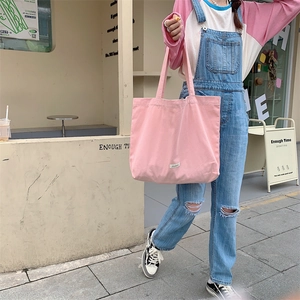 Detailed close-up of a large pink canvas tote bag with a white brand label and wide strap