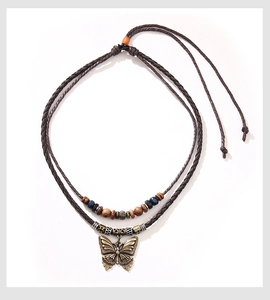 Détail d'un pendentif papillon vintage sur un collier de perles en bois tressé à la main
