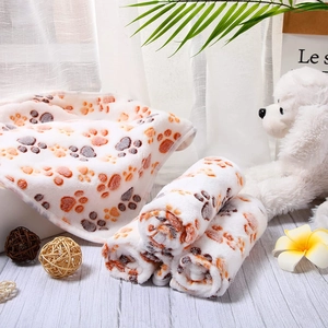 Detail of soft flannel pet blanket with colorful paw prints on a wooden floor