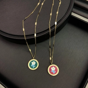 Gros plan de colliers dorés avec pendentifs ronds en émail floral vert et rose