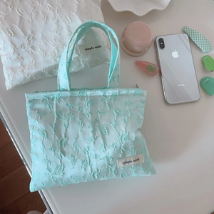 Detail of mint green jacquard mini handbag with woven texture and Simple Wish label