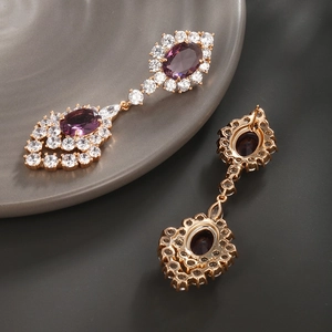 Détail macro de boucles d'oreilles en pierres violettes, placage or rose et zircons