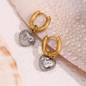 Detail of two-tone heart pendant earrings with water droplets showing waterproof feature