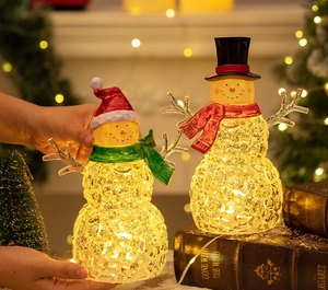 Close-up of dual glowing LED crystal snowmen ornaments on vintage books for Christmas decor