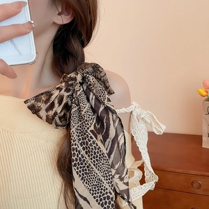 Detail showing a stylish leopard print silk scarf braided into a ponytail hairstyle