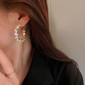 Elegant gold hoop earrings with emerald-cut crystals shown on a female model