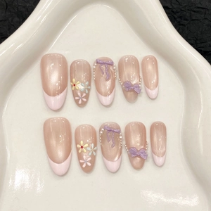 Handmade taro bow press-on nails with 3D pearls and floral patterns on white tray