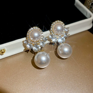 Close-up of luxury gold earrings featuring white pearls and shimmering diamonds