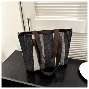 Detail of striped canvas tote bag with woven texture and brown handles on table