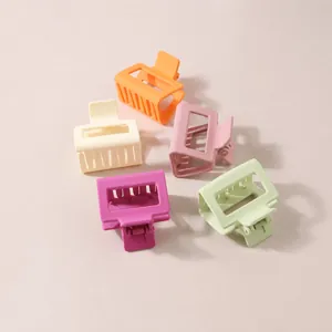 Macro view of assorted matte square hair claws in macaron colors on a magazine page