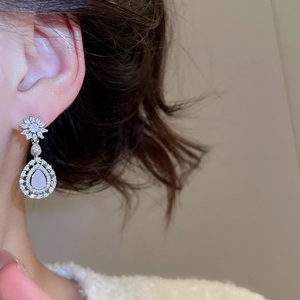 Détail de la boucle d'oreille fleur en zircon sur modèle montrant son éclat élégant