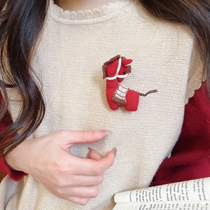 Detail of a handmade red fabric horse brooch with knitted textures on beige sweater