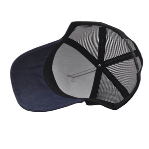 Detail of the black trucker hat featuring breathable mesh and adjustable snapback closure