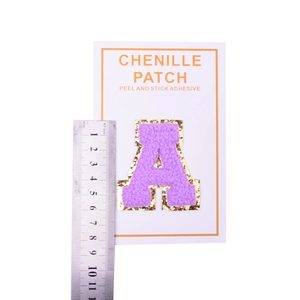 Close-up of a purple chenille letter A patch with gold glitter edge and adhesive back