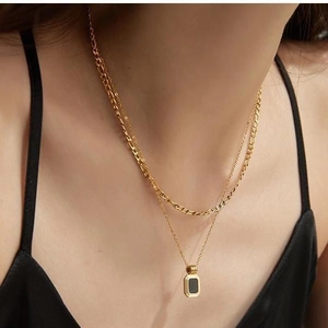 Double-layered gold necklace with thick chain and black rectangular pendant on model