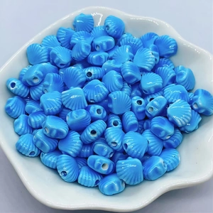 Detailed top view of blue scallop-shaped ceramic beads for DIY jewelry making in a dish