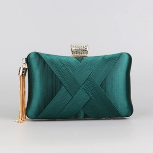 Detail of dark green silk clutch with elegant cross pleats and a gold tassel charm