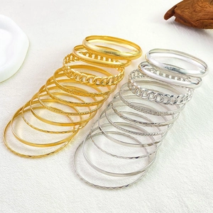 Detail of stacked gold and silver alloy bangles featuring hammered and embossed textures