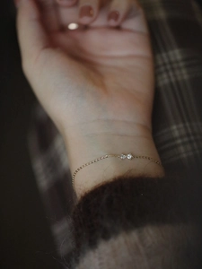 Close-up of S925 silver bow bracelet with heart zircons on a model's wrist