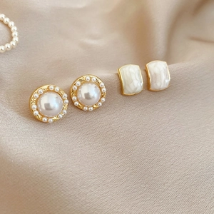 Detailed macro of vintage pearl stud earrings on a silk fabric background texture