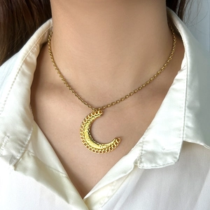 Gros plan du collier avec pendentif lune doré et texture gravée sur un mannequin