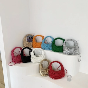 Unique woven knot shoulder bags in multiple colors like pink black and gold displayed on steps