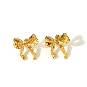 Macro shot of gold bow knot earrings featuring polished metallic texture and stud backing