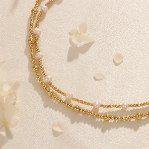 Detail of layered freshwater pearls and gold beads on soft beige silk fabric
