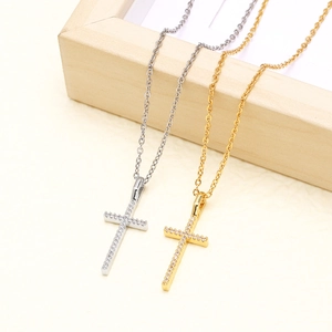 Minimalist gold and silver cross necklaces with zircon inlays on light wood frame