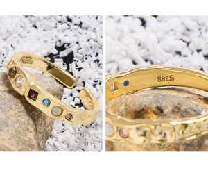 Close-up of S925 silver stamp on gold ring with textured surface and colored zircon