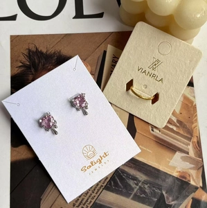 Detailed view of pink heart zircon stud earrings and a minimalist gold band on display cards