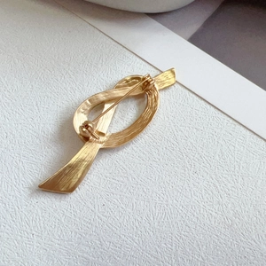 Vintage golden knotted brooch with refined metallic texture and secure pin closure