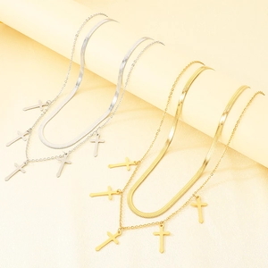 Detailed view of layered stainless steel cross necklaces in gold and silver finishes