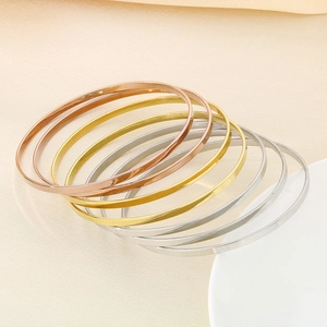 Detailed close-up of stacked stainless steel bangles in rose gold, gold, and silver finishes