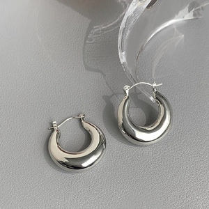 Detailed view of chunky silver hoop earrings with a high-polish metallic finish