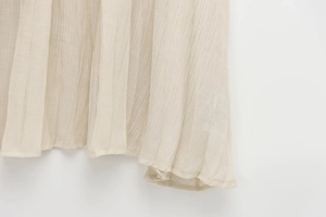 Gros plan de l'ourlet plissé beige avec coutures fines et texture de tissu de qualité