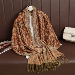 Detail of luxury paisley pattern scarf with elegant tassels on leather surface
