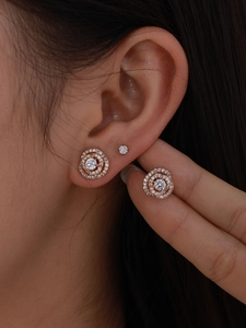 Dettaglio di orecchini a spirale in oro rosa con pavé di zirconi su una modella
