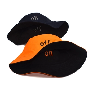 Detail of reversible cotton bucket hats featuring on and off letter embroidery in black and orange
