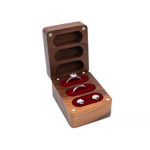 Macro shot of dark walnut wood ring box featuring three slots and red velvet lining