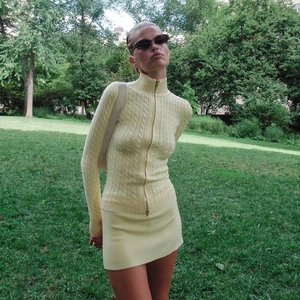 Gros plan sur l'ensemble deux pièces jaune tricoté avec cardigan zippé et mini-jupe assortie