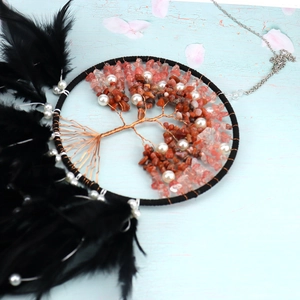 Macro shot of tree of life charm with red crystal stones and black feathers