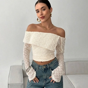 Close-up of white off-shoulder lace top with pearl embellishments and flared sleeves